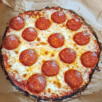 Keto cottage cheese egg pizza crust topped with mozzarella and pepperoni on a rustic wooden table.